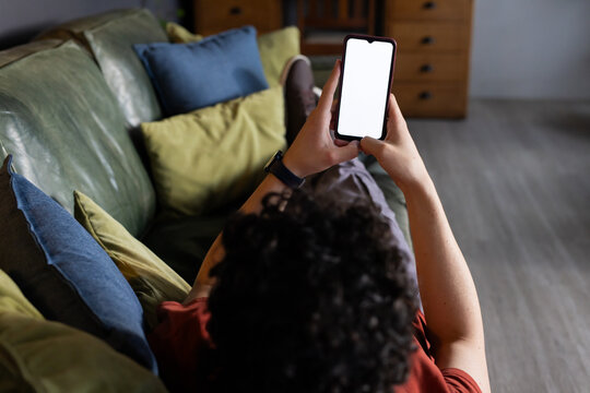 Smartphone is being held toward camera on green leather sofa with blue, yellow, green pillows