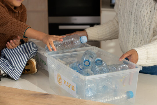 Diverse family with child sorting recyclables on kitchen counter with plastic bin and water bottles