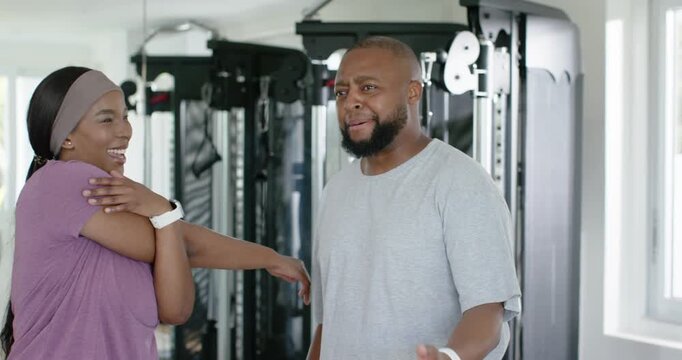 Couple turning after man joking, woman stretching arm in purple top, laughing by weight machine