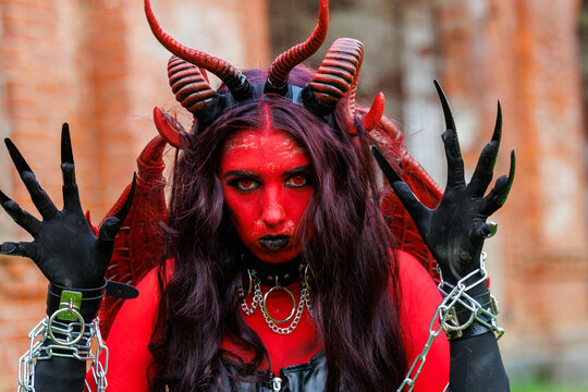Scary Red Demon Woman with Horns and Wings in Halloween Costume