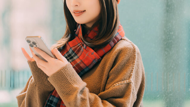 冬の街角でスマートフォンを使う笑顔の女性