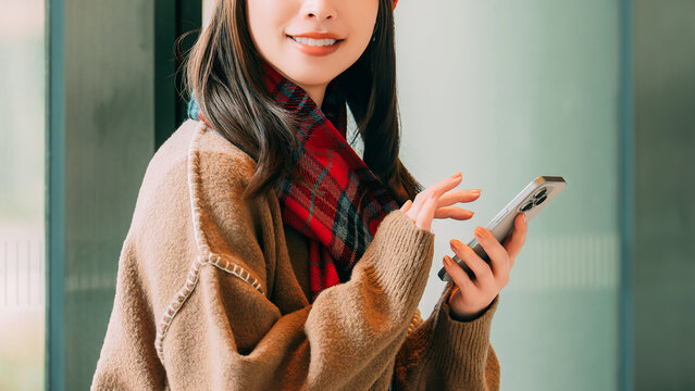 冬の街角でスマートフォンを使う笑顔の女性