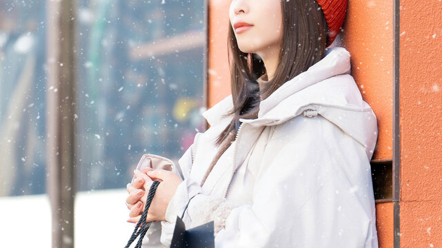 雪の降る冬の街角に立つ笑顔の女性
