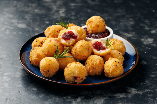 Party appetizers with brie cheese, cranberry sauce and fresh rosemary on crackers, served on plate