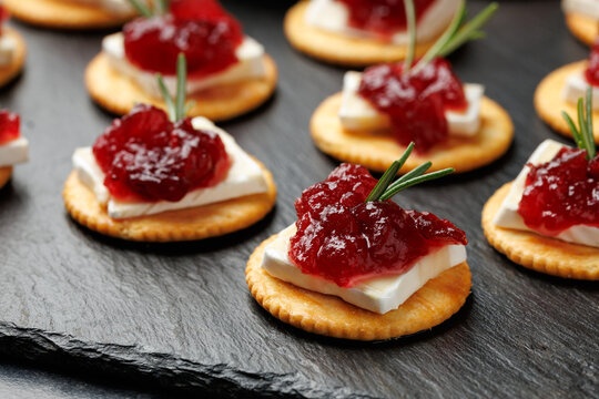 Party appetizers with brie cheese, cranberry sauce and fresh rosemary on crackers