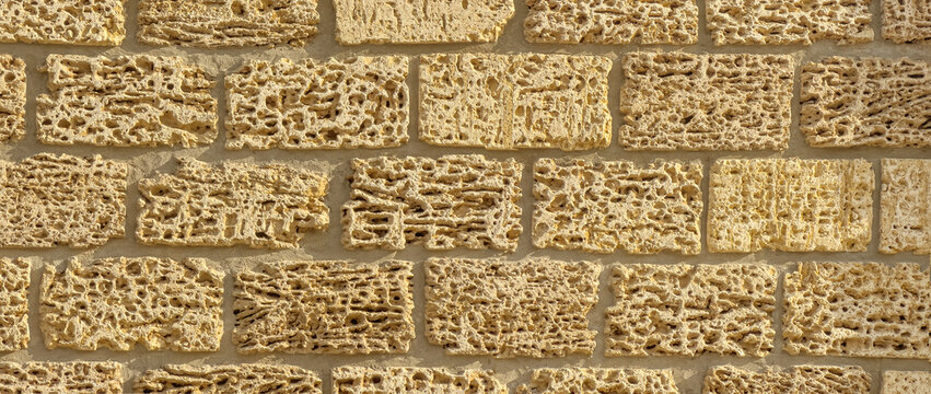 Porous coquina limestone wall with warm stone block texture