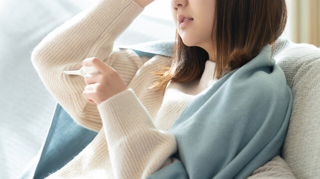 熱を測る体調不良の女性