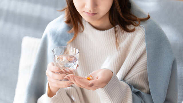 薬を飲む体調不良の女性