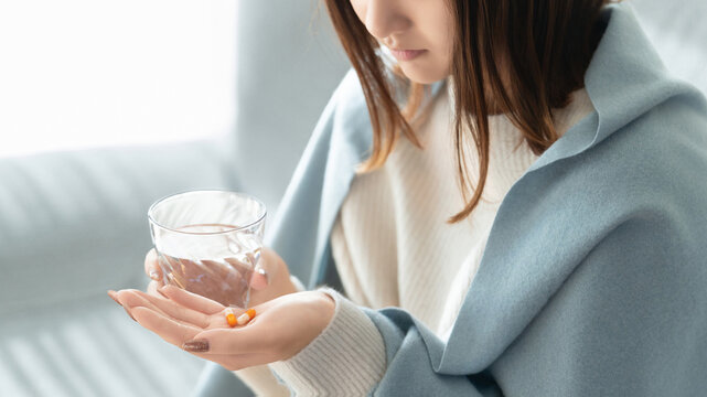 薬を飲む体調不良の女性