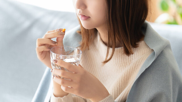 薬を飲む体調不良の女性
