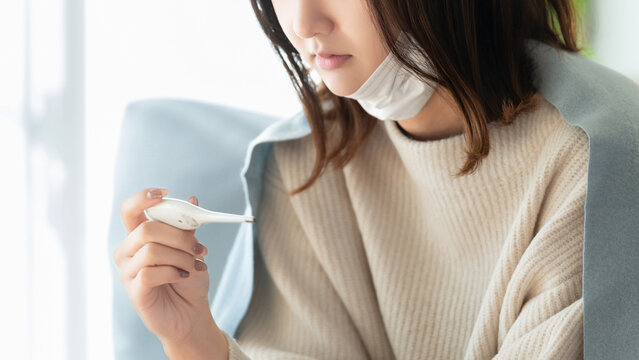 熱を測る体調不良の女性