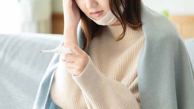 熱を測る体調不良の女性