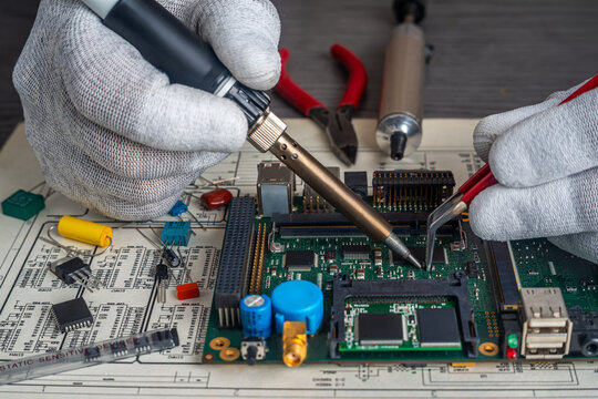 Technicians perform assembly and quality control on a circuit board in a manufacturing workshop