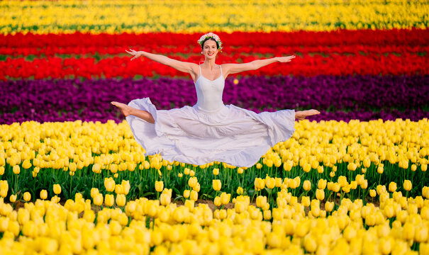 Ballet white dancer leaping in colorful tulip field outdoors