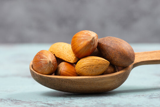 Nuts mixture, hazelnuts, peanuts and almonds in a wooden shovel, healthy food, nutrition, ingredients for baking, protein and antioxidants