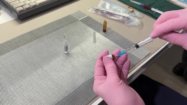 Woman in medical gloves drawing medication from ampule into syringe at home