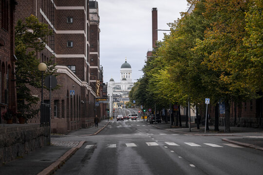 Helsinki, Finland - 22 September 2026: View of Helsinki Cathedral in the distance, framed by historic brick buildings and autumn trees lining the street.