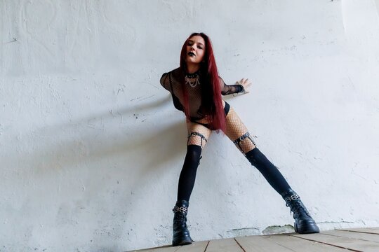Gothic Fashion Woman in Fishnet Outfit Posing Against Geometric Metal Structure