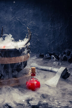 Vertical shot of smoking witch cauldron with red potion bottle