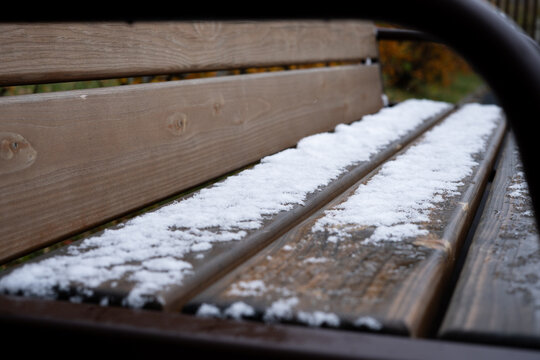 Snow-covered wooden bench in a park during winter  