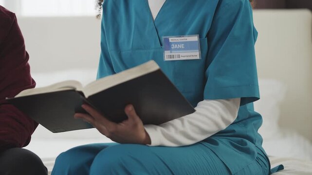 Female caregiver reads book to elderly man, providing home care support