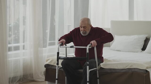 Elderly man with disability uses walking frame in retirement home ward