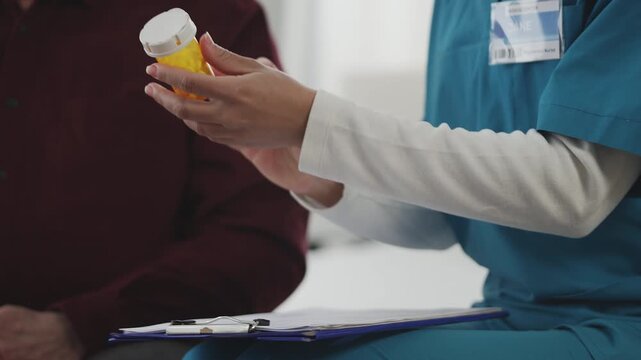 Female doctor prescribes and gives vitamins to elderly man in nursing home