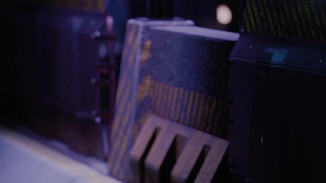 A model train operates on tracks inside a dim space. The train moves through a tunnel surrounded by walls in shades of purple. The scene shows details of the setup and environment.