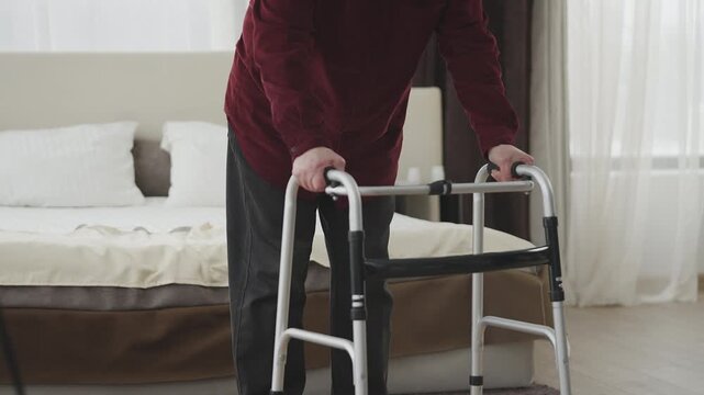 Senior retirement home patient uses walking frame to move around the ward