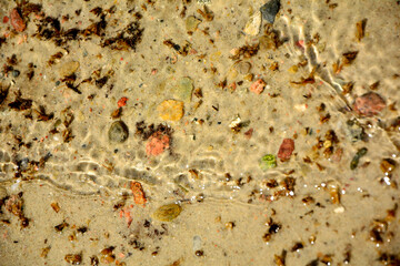 łagodne fale przejrzystej wody na piasku, delikatne, połyskujące w słońcu fale na piaszczystym brzegu, waves of clear water on the sand, deep waves on the shore © kateej