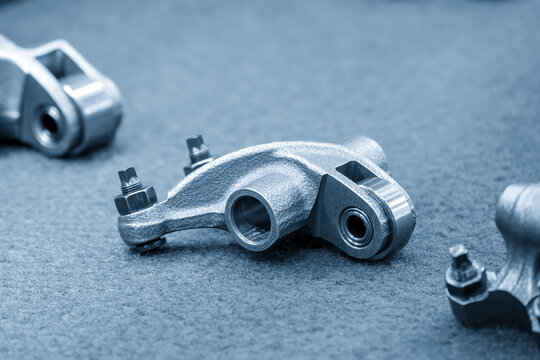 Close-up of automotive roller rocker arm parts in a modern blue tone scene
