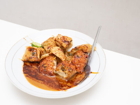Indonesian traditional food from West Java region called Batagor stands for baso tahu goreng, a fried fish cake with tofu in peanut butter sweet-hot sauce served in a white plate