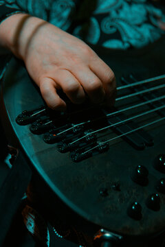 Close up of a musician plucking strings on a multi string electric bass guitar
