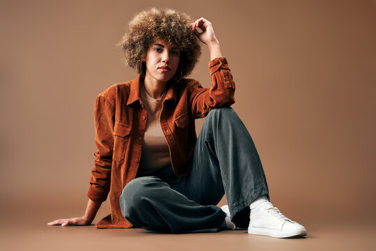 Young woman sitting in casual fashion studio portrait.