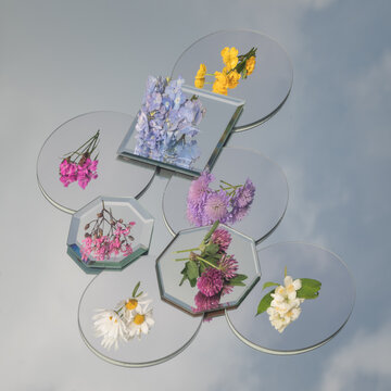 artistic still life with spring flowers on several mirrors with their reflection and blue sky