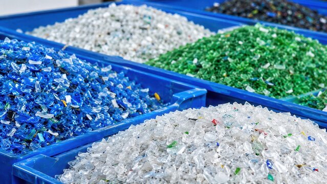 Sorted plastic flakes in blue bins ready for recycling and reuse at modern waste processing facility