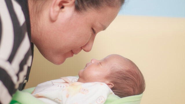 Maternal love, bonding, intimacy and family tenderness. Close up of a mother gazing affectionately at her newborn baby, highlighting their face to face connection in soft natural light.