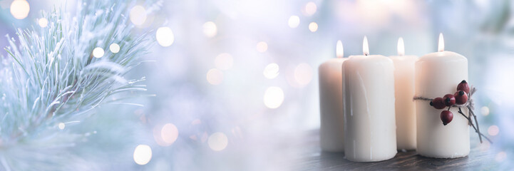 Four glowing candles in glittering winter atmosphere with soft bokeh. Festive outdoor decoration for christmas greetings and seasonal celebrations. Space for text. © gudrun