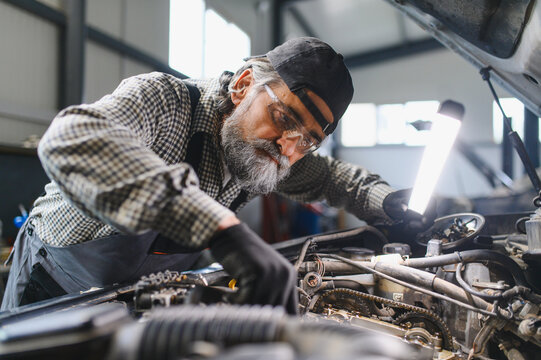Auto mechanic inspecting car engine during diagnostics and repair