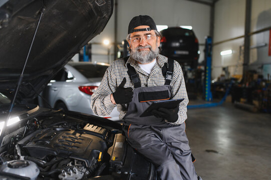 Experienced auto mechanic holding tablet giving thumbs up