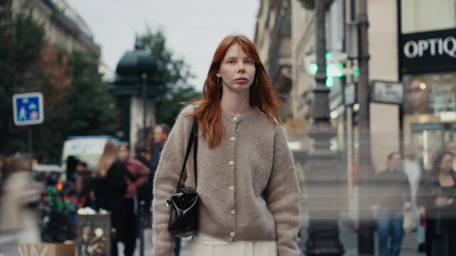 Stylish redhead woman standing on a busy city street in paris