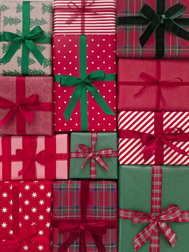 Red and green Christmas presents arranged as a decorative background. Festive wrapped Christmas gift boxes with ribbons and holiday patterns.	