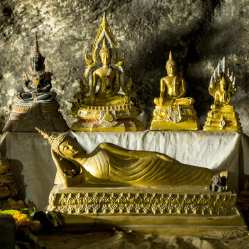 Altar with reclining Buddha and golden statues inside limestone cavern of Tham Krasae cave, Thailand