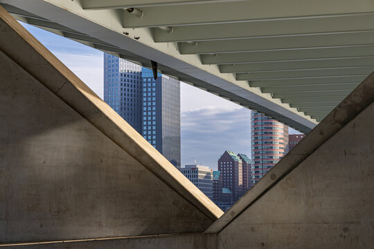Rotterdam, Netherlands - 13 December 2025: View of Erasmusbrug framed by concrete structural elements, with modern skyscrapers visible in the background under a cloudy sky.