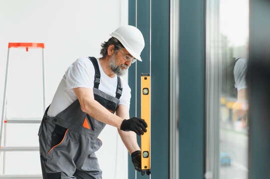 Professional worker installing window glass leveling building home