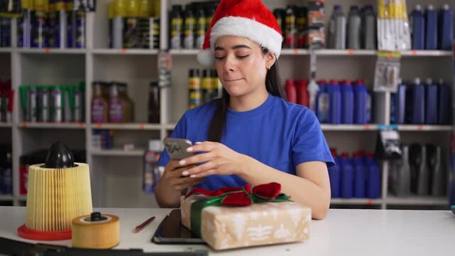 Auto parts store worker in santa hat using smartphone and smiling