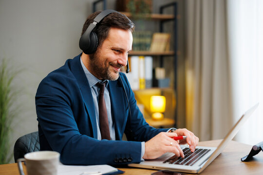 Businessman wearing a headset and typing on a laptop in a modern office