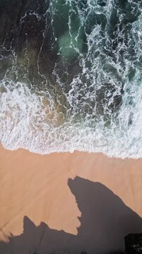 Quiet coastal paradise. Hidden seaside cove with sandy shores. Remote rocky shore featuring soft pink sands. Secluded cliff edge beach with peachcolored grains and calm waves, vertical video
