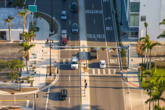 People walking briskly across urban crossroad in Sarasota, Florida, during peak hours, illustrating movement, speed, and the daily flow of city transportation.
