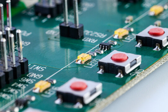 Close up of electronic printed circuit board with buttons resistors and pin headers